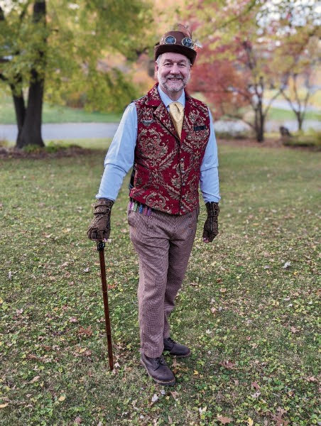 Shawn in a steampunk outfit with a decorative vest, top hat, and cane